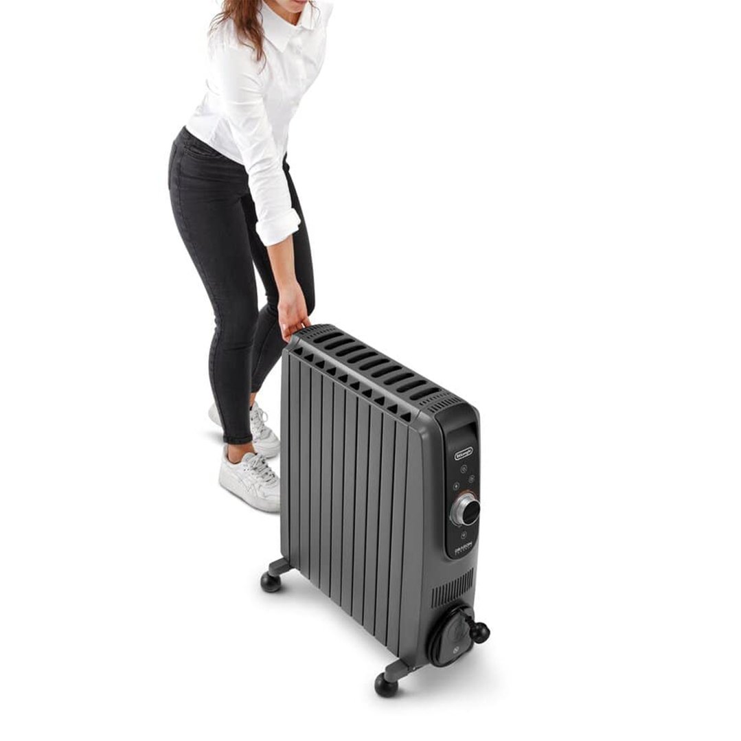 Woman in black jeans and white shirt moving a grey oil column heater