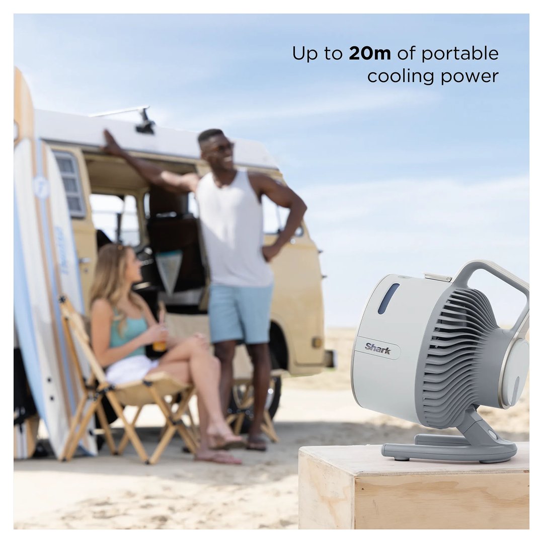Shark portable fan on a wooden box at the beach with people and a van