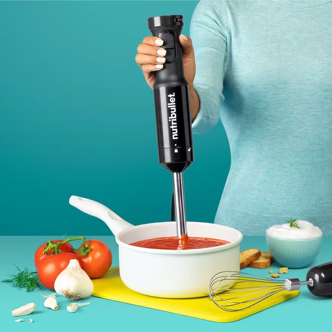 Person using a NUTRiBULLET immersion blender to blend sauce in a pot