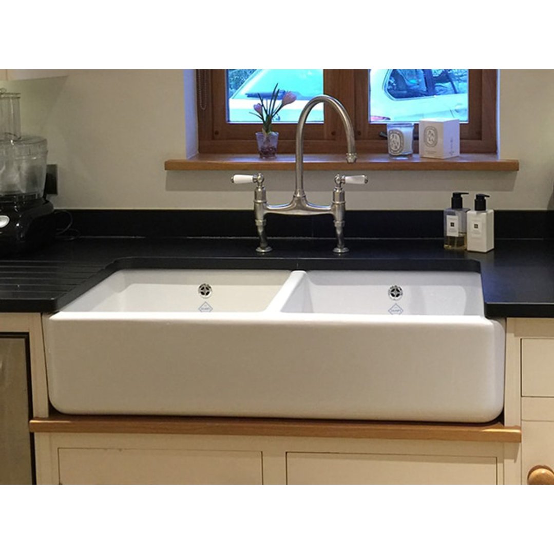 Double bowl sink installed in a kitchen with black countertop and window