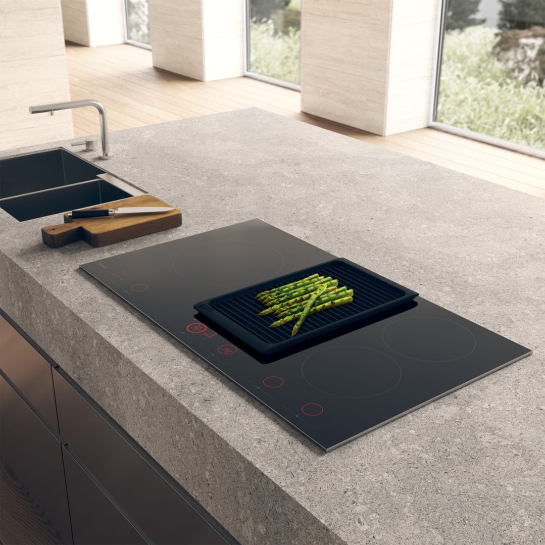 Induction hob cooktop with asparagus on a grill pan in a modern kitchen