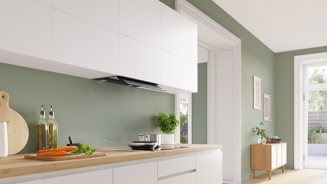 Integrated rangehood in a modern kitchen with white cabinets and green walls