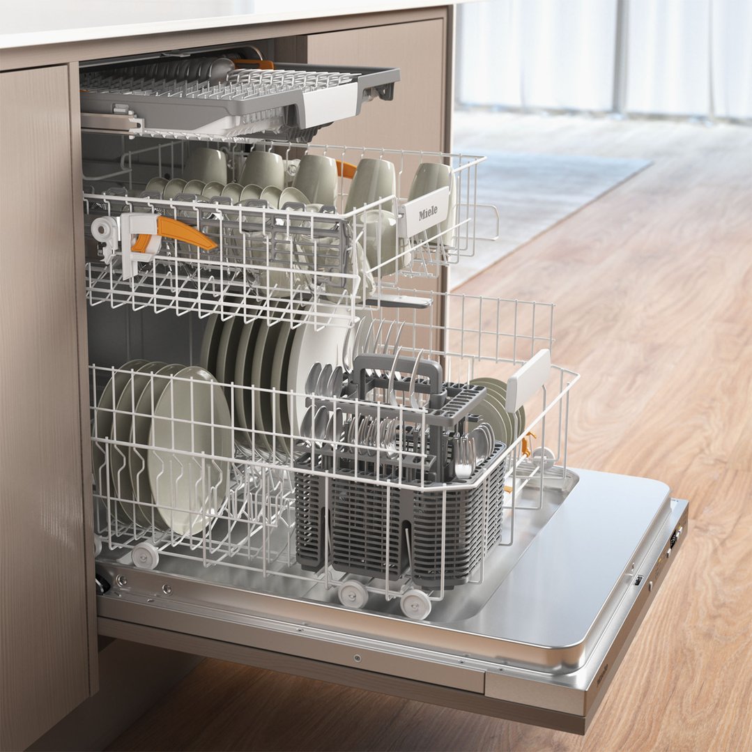 Open dishwasher with racks full of dishes and cutlery in a kitchen setting