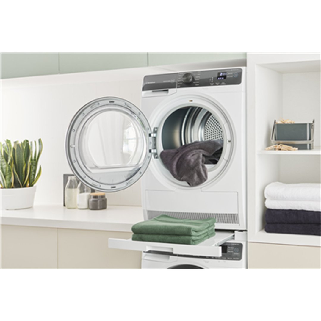 White dryer with open door and dark laundry in a styled laundry room