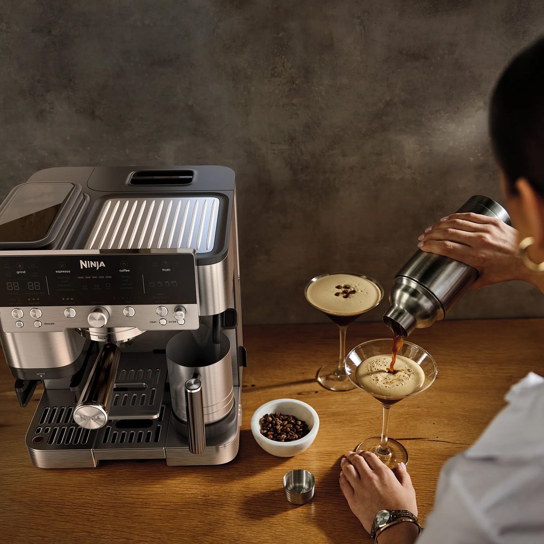 Person pouring coffee from a shaker into a martini glass next to a coffee machine