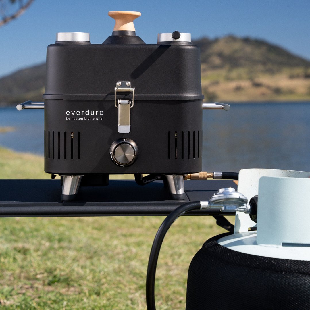 Everdure bbq accessory with hose and regulator connected to a gas bottle outdoors