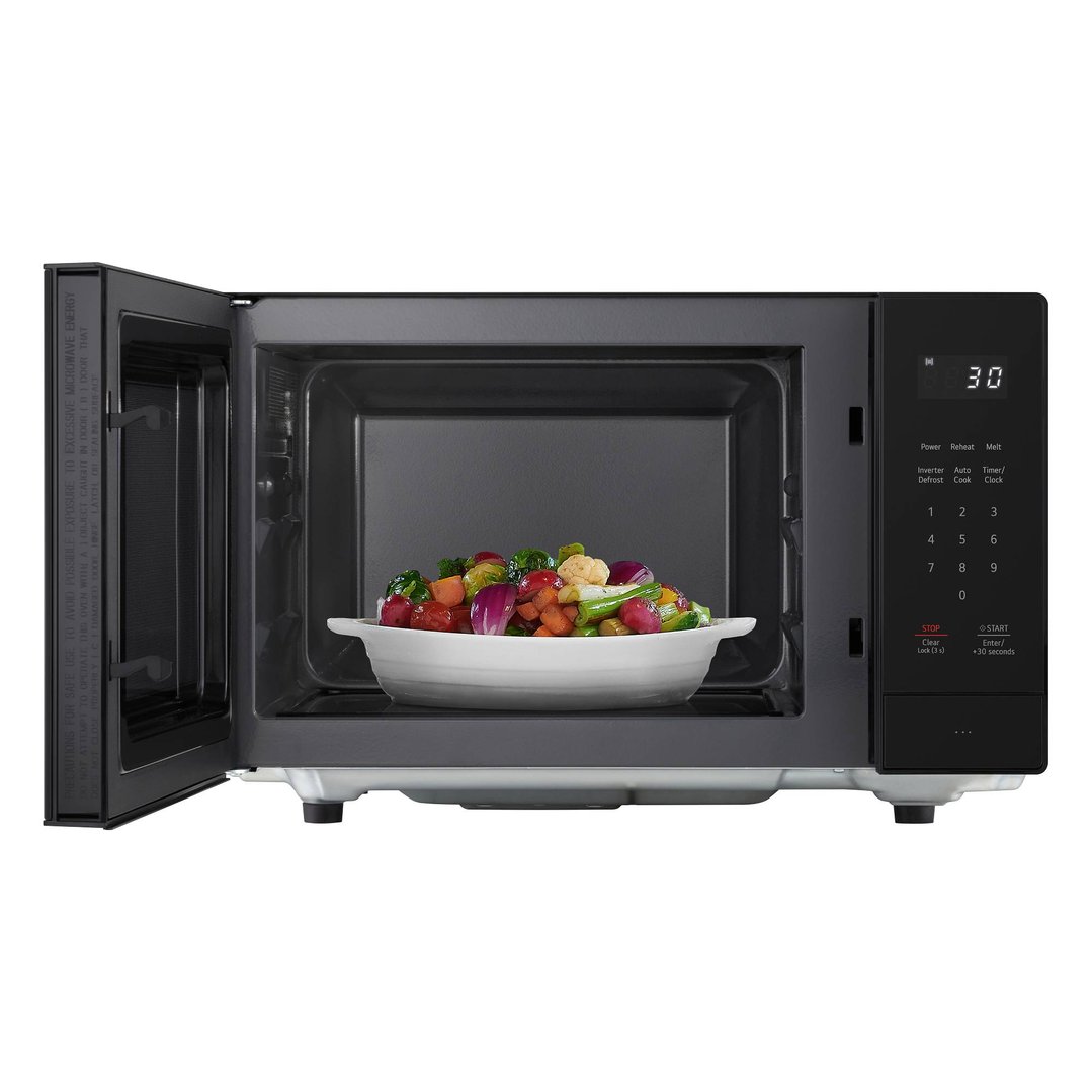 Black LG microwave with door open, bowl of vegetables inside