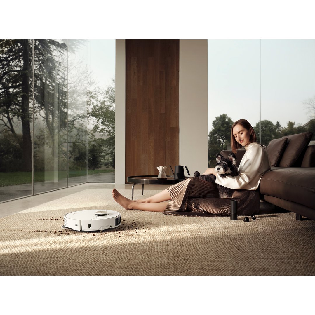 Woman with dog on floor next to robot vacuum and mop cleaning spills