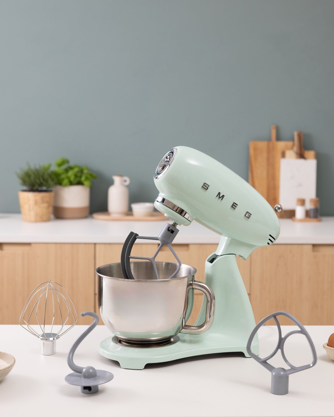 Pastel green SMEG food mixer with accessories on a kitchen counter