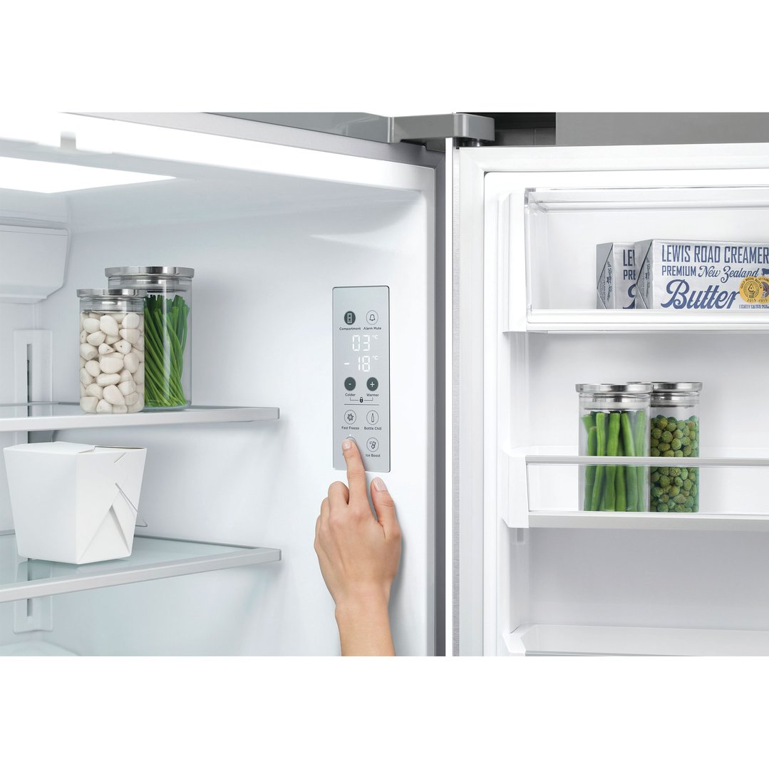 Hand adjusting the temperature controls on the interior of a refrigerator freezer