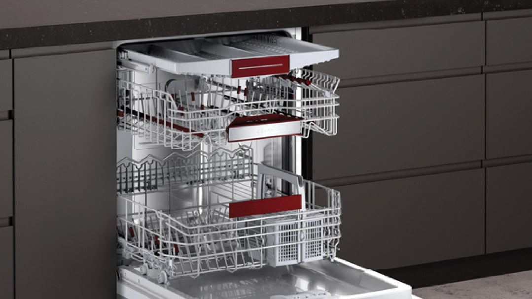 Open built-under dishwasher with three racks in a dark kitchen setting