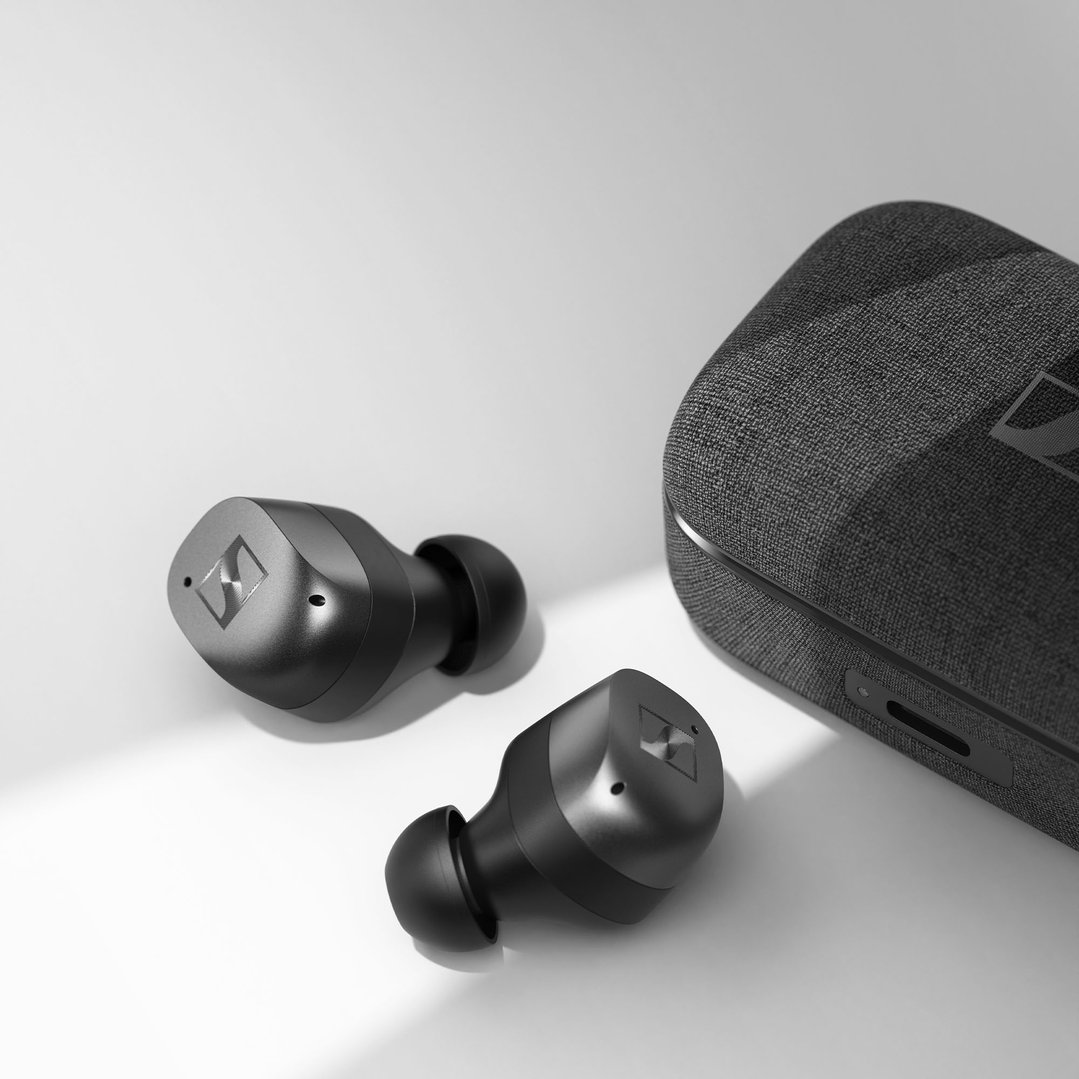 Two Sennheiser Momentum True Wireless 4 earbuds and charging case on a white surface