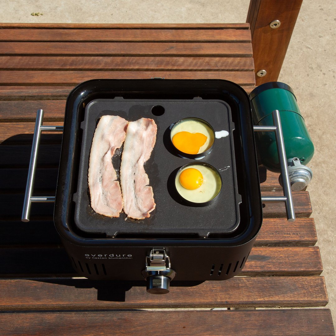 Everdure Pro Flame 360 Solid Plate cooking bacon and eggs on a wooden bench