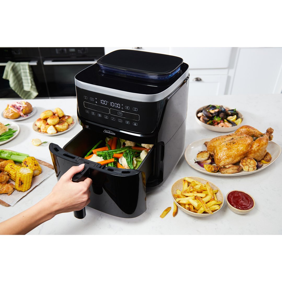 Hand pulling out the basket of a Sunbeam SteamFry Air Fryer filled with vegetables