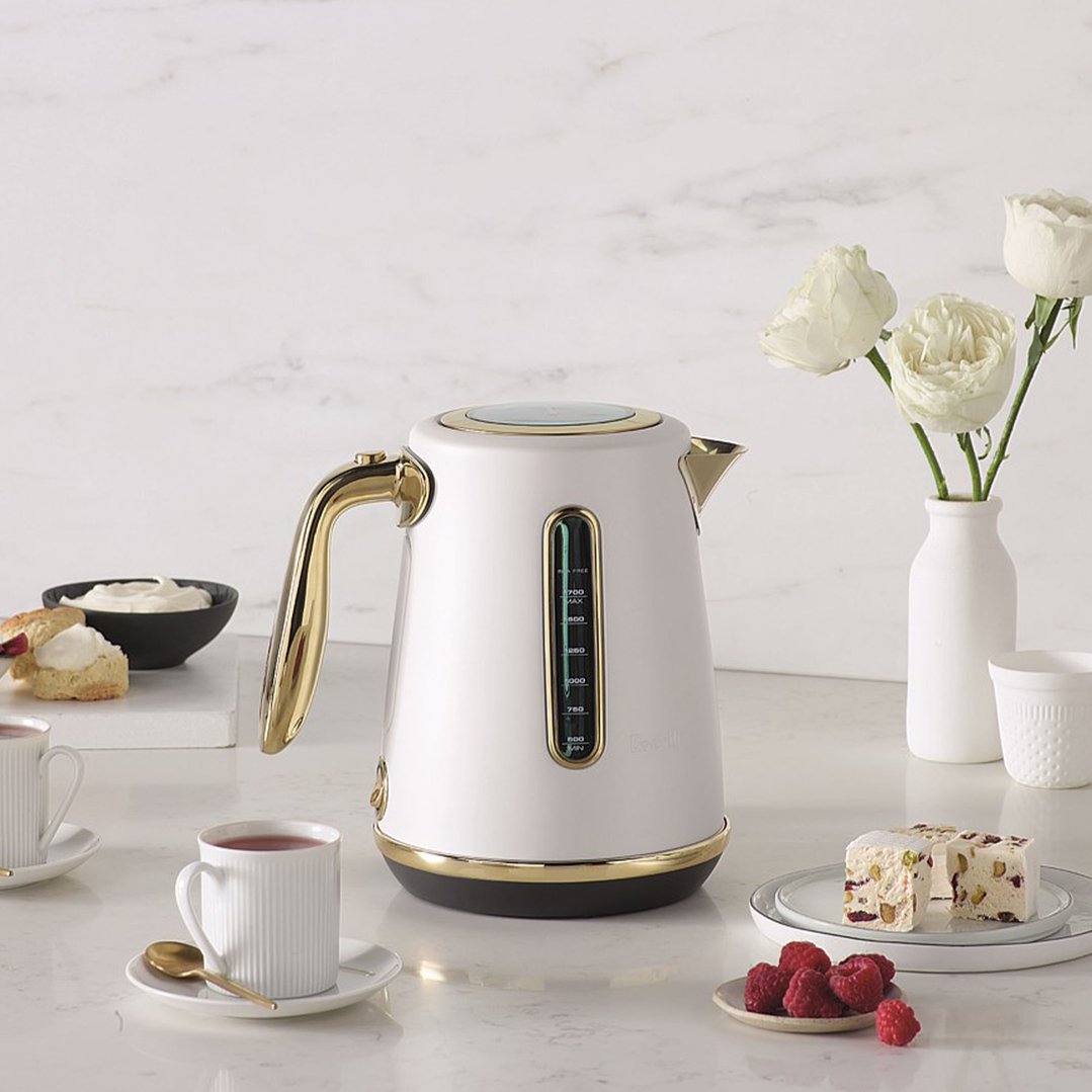 Breville Soft Top Luxe Kettle on a white marble counter with tea and snacks