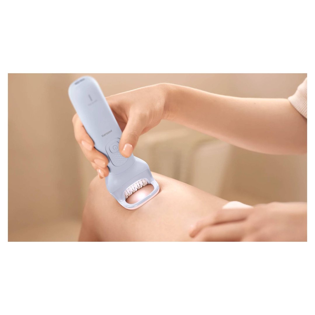 A person's hand holding a Philips epilator to their leg