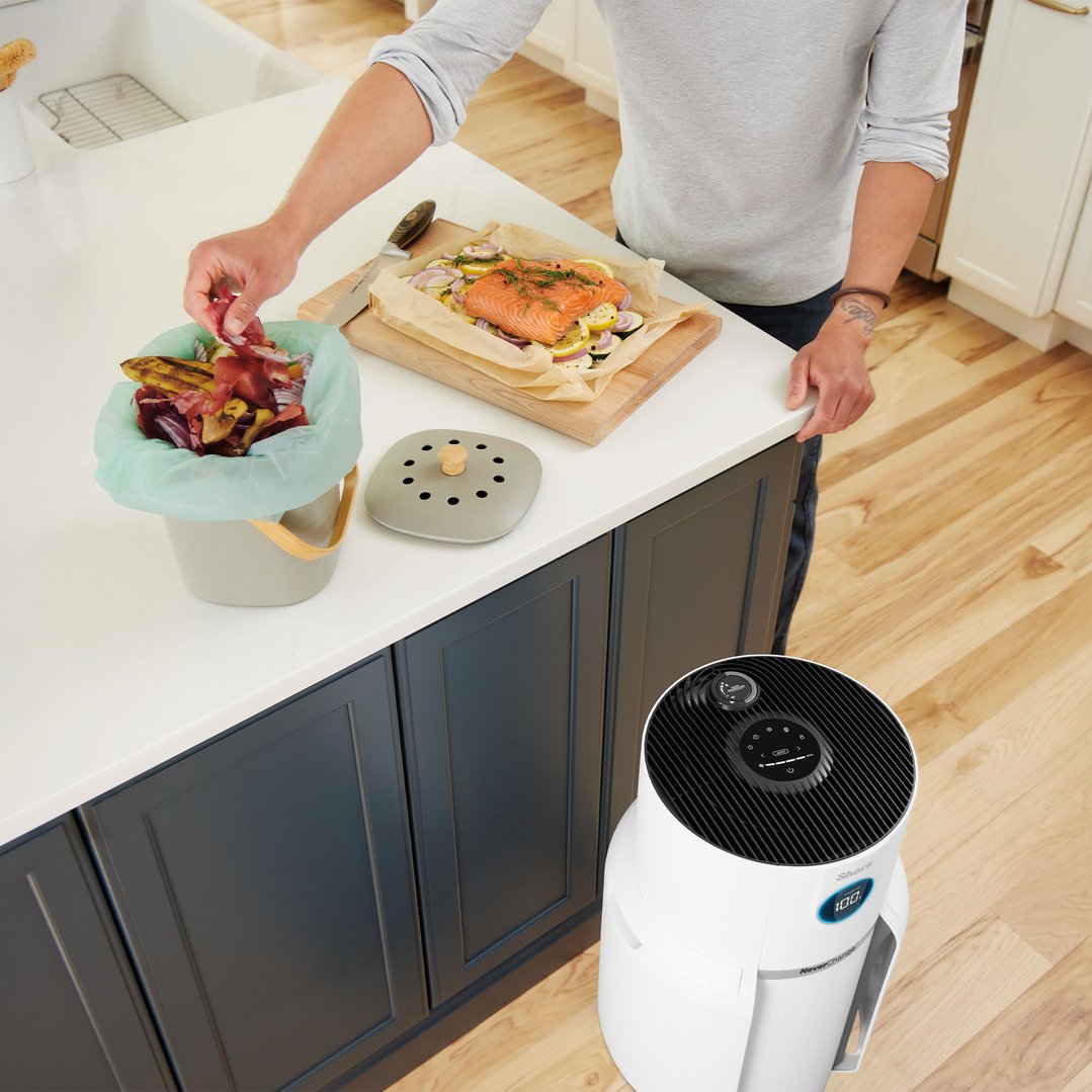 Man preparing food in kitchen with air purifier on floor
