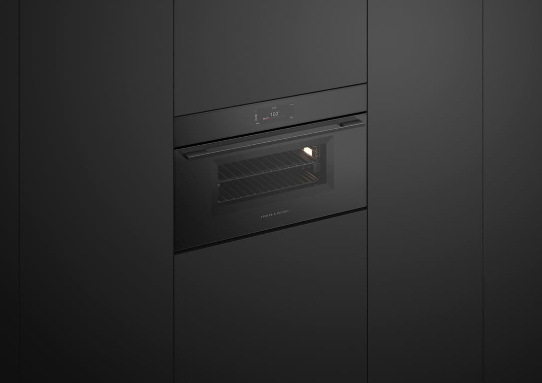 Black compact combi-steam oven built into dark cabinetry with door slightly ajar