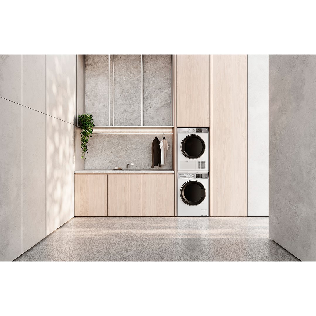 Two heat pump dryers stacked in a modern laundry room with light wood cabinets