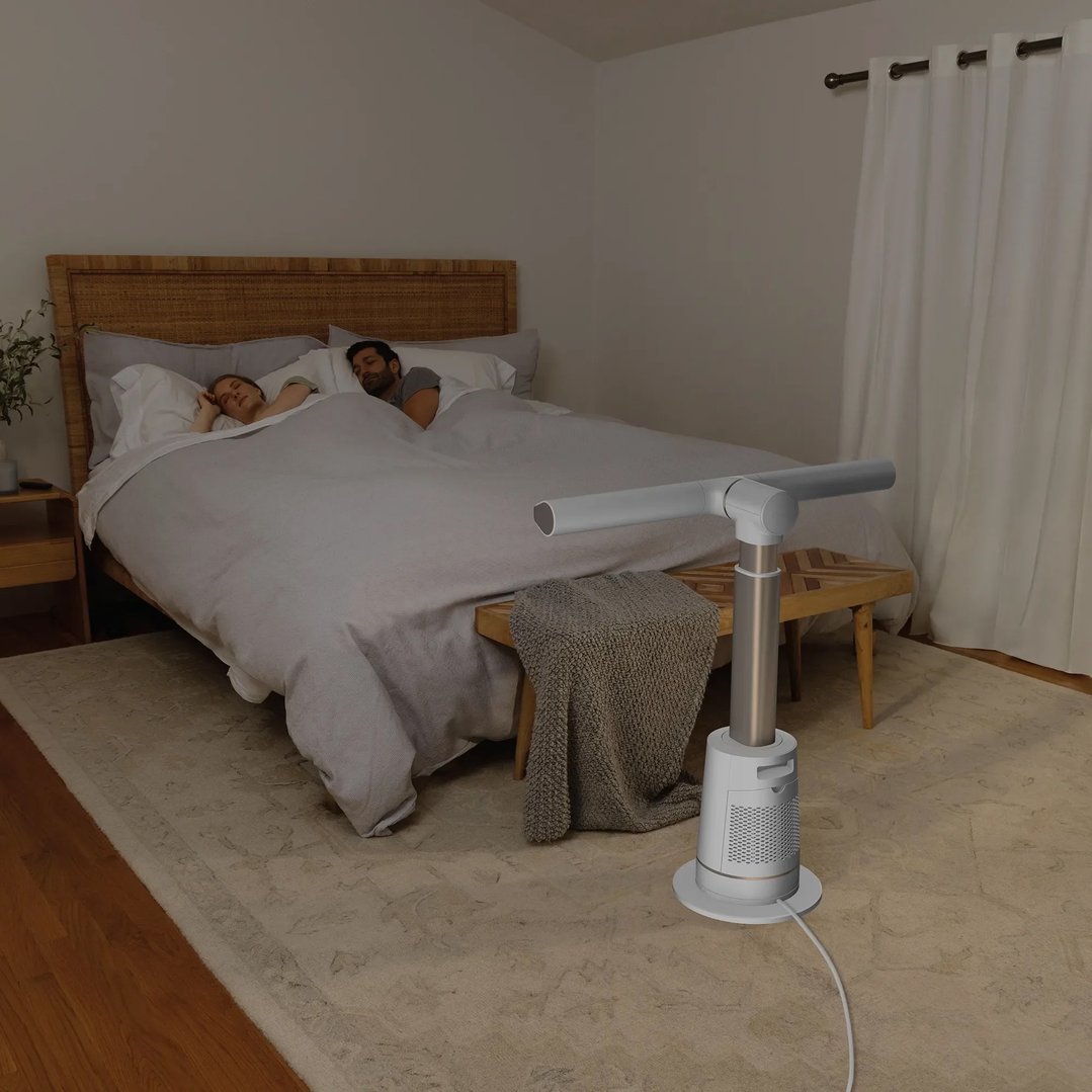A white TurboBlade fan in a bedroom with a couple sleeping in bed