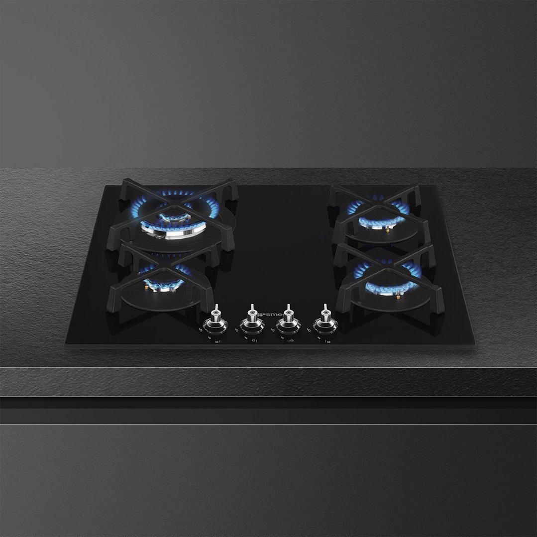 Black glass cooktop with four gas burners and controls, installed in a dark kitchen