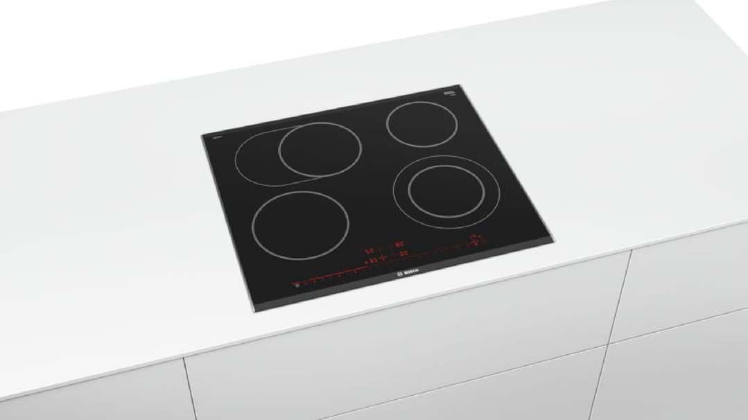 Black ceramic cooktop with four cooking zones built into a white kitchen bench