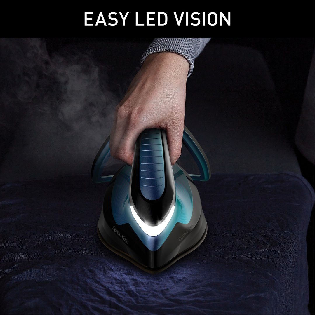 Hand holding a TEFAL Express Vision Steam Station iron with LED light on dark fabric