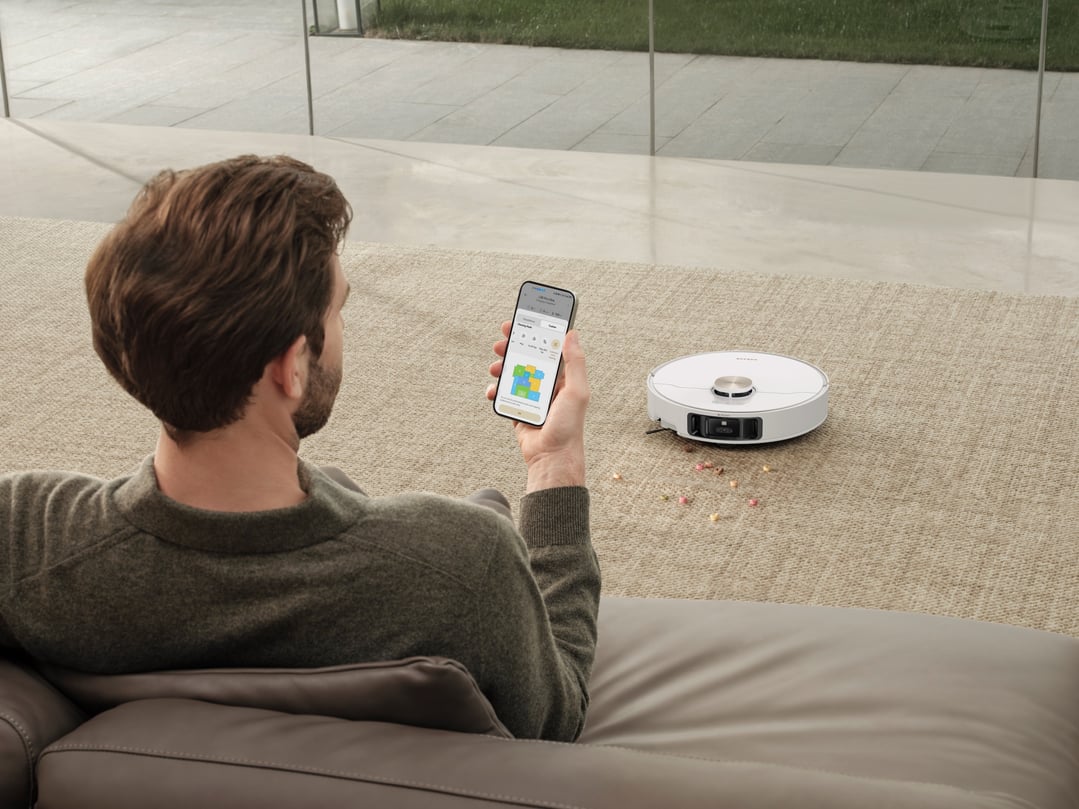 Man on sofa using phone to control L50 Ultra robot vacuum and mop