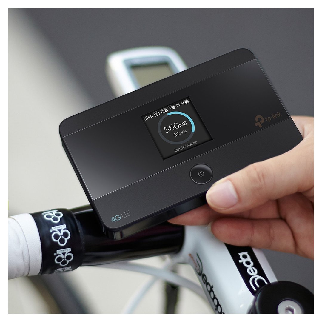 Hand holding a TP-LINK 4G LTE Advanced Mobile Wi-Fi on a bicycle handlebar