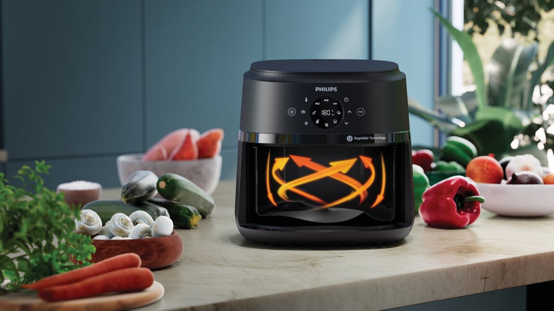 Philips airfryer on a kitchen counter with vegetables and ingredients
