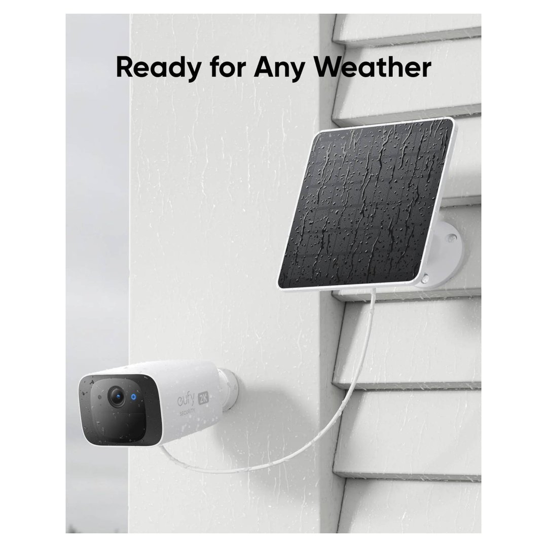 Security camera and solar panel mounted on a white house wall in the rain