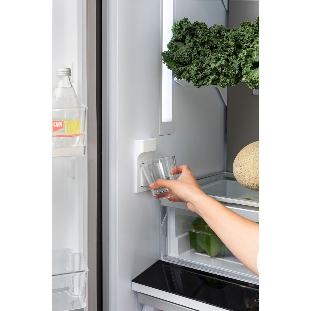 Hand filling a glass with water from the integrated fridge dispenser