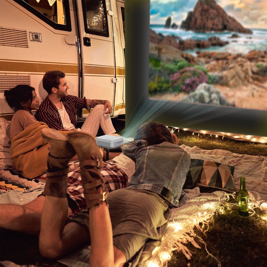 Friends watching a movie projected onto a large outdoor screen at night