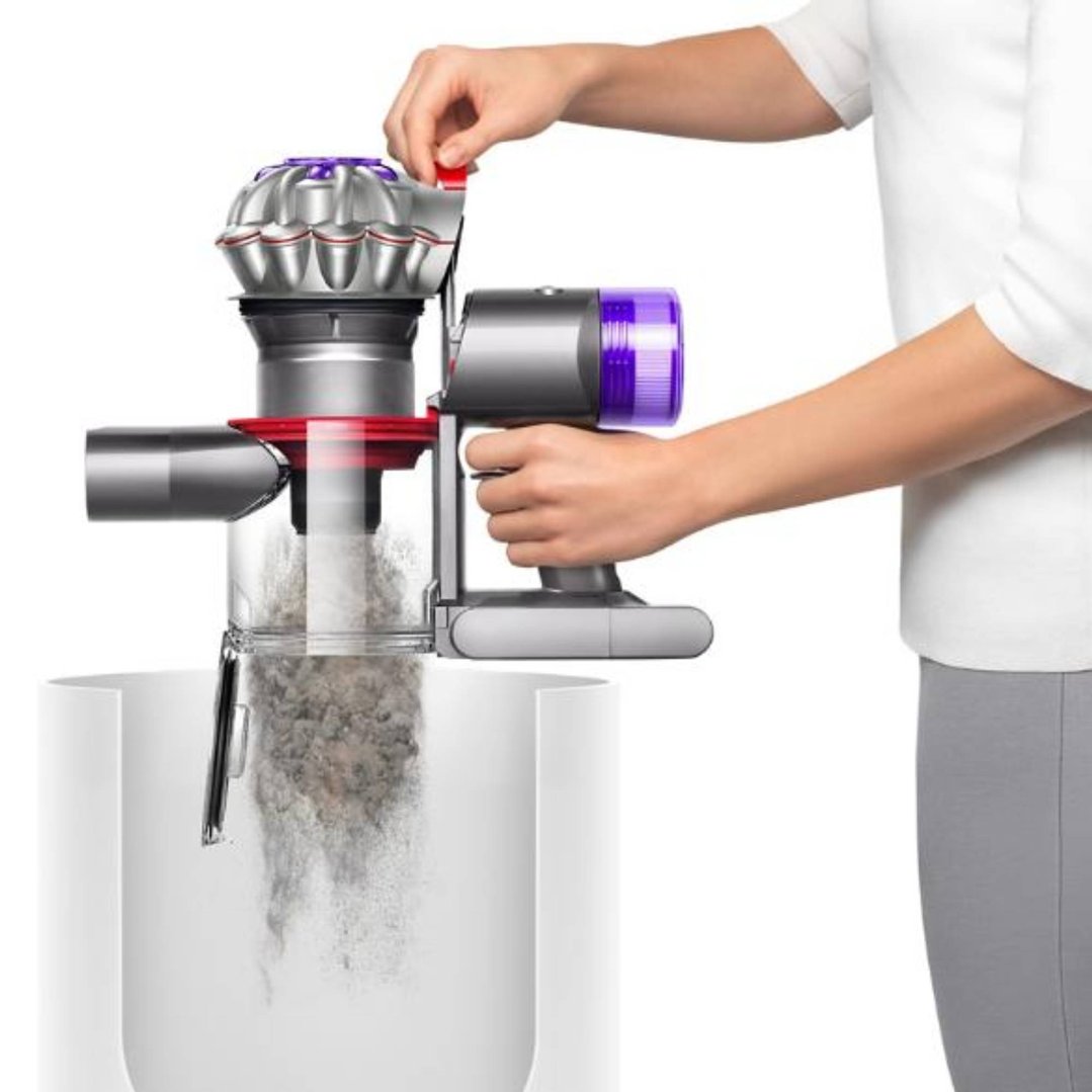 Person emptying the Dyson V8 Advanced Vacuum into a white bin