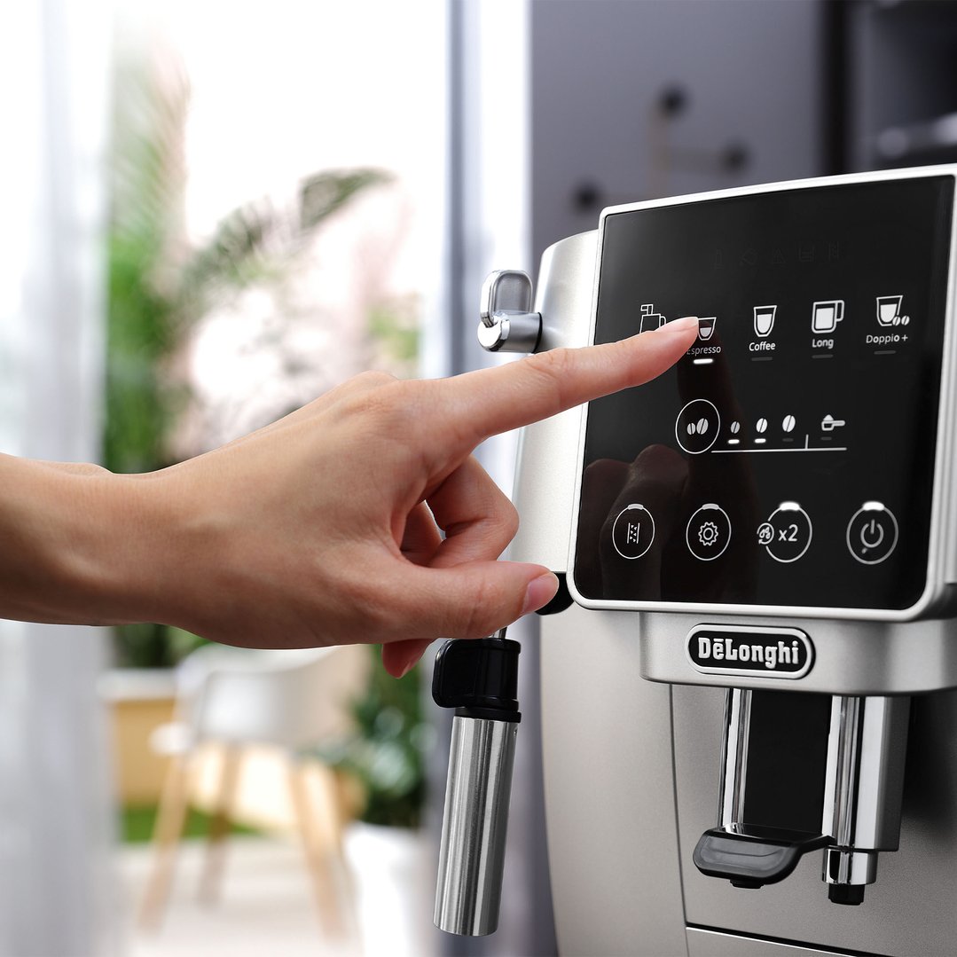 Hand touching the display of a coffee machine to select espresso