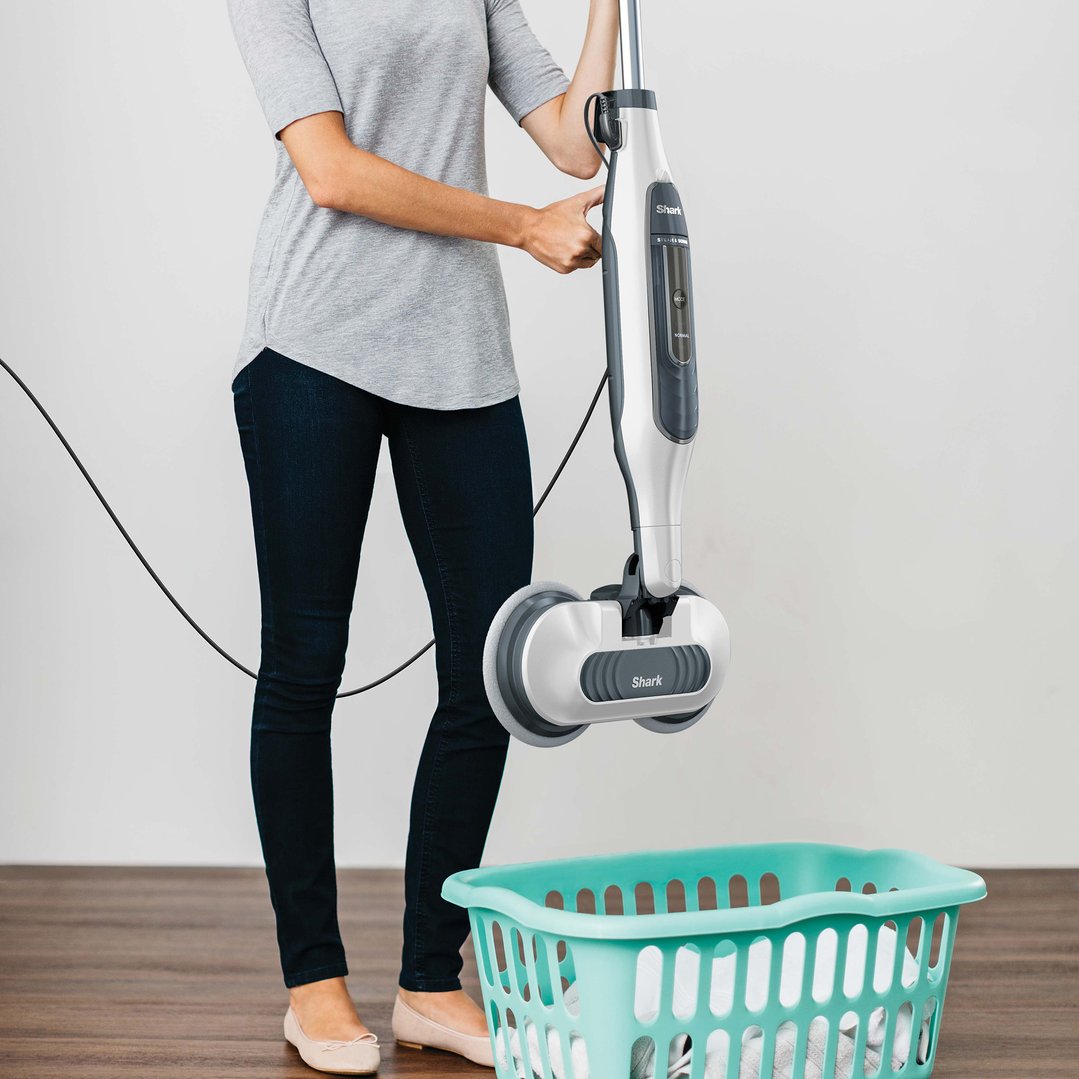 Woman holding a Shark Steam and Scrub Mop next to a laundry basket