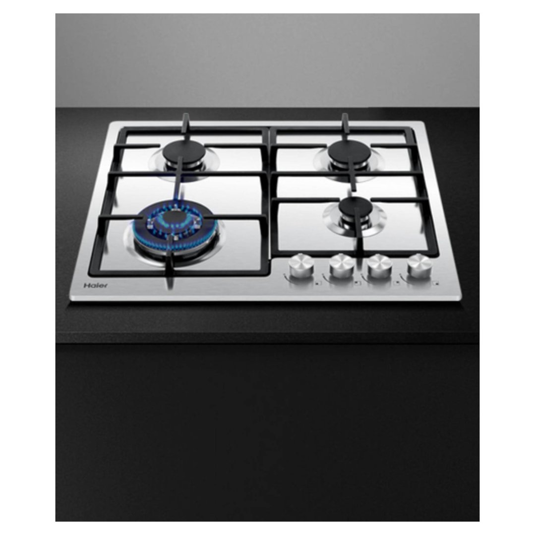Stainless steel gas cooktop with one burner lit, on a dark countertop