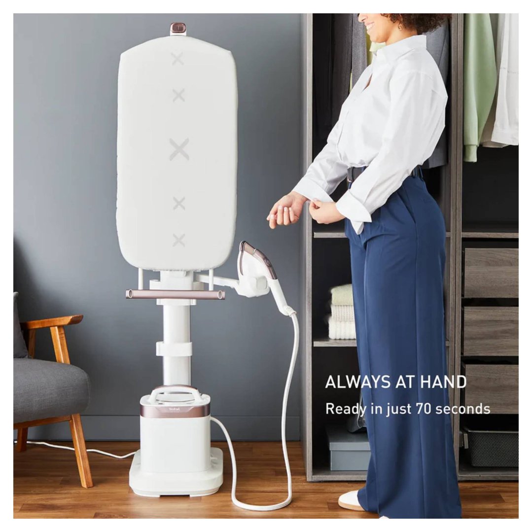 Woman adjusting cuff next to a garment steamer in a bedroom closet
