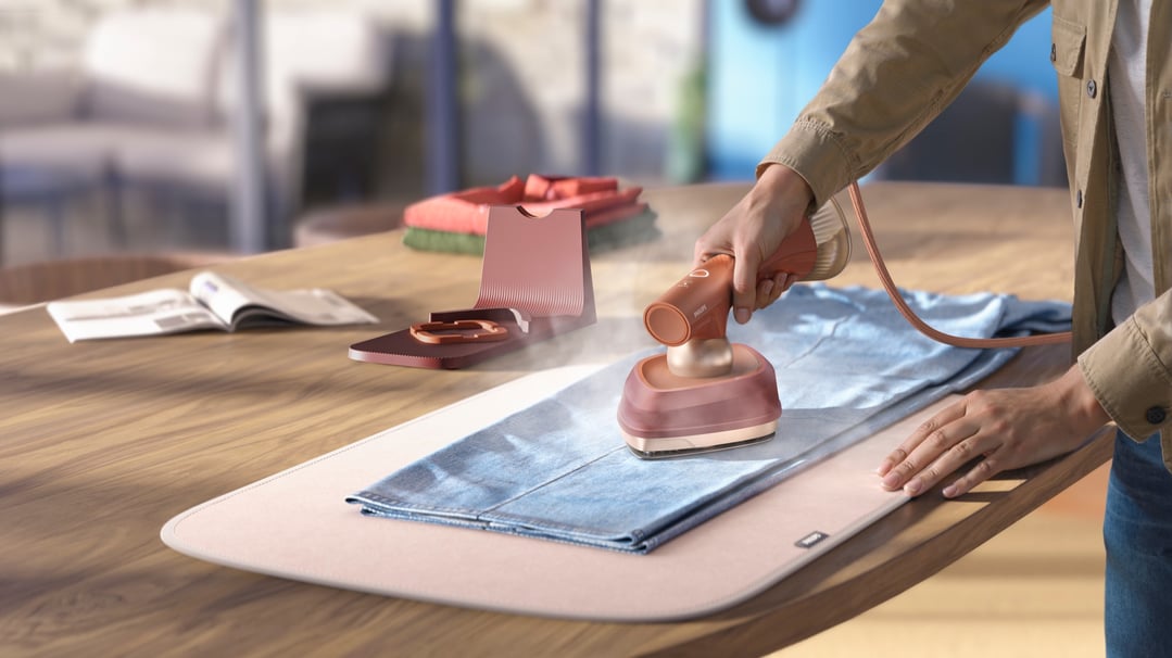 Person using a Philips OneTurn Hybrid Iron & Steamer on a light blue shirt