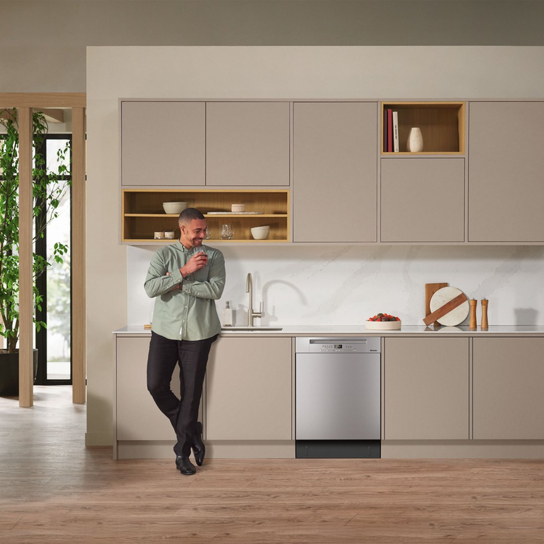 Man leaning on kitchen counter next to a built-under dishwasher