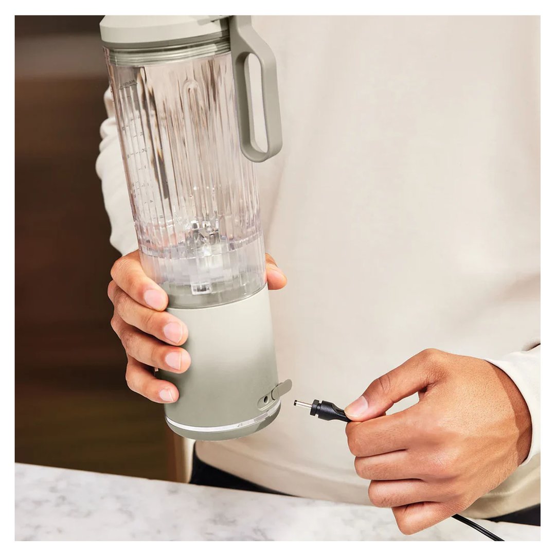 Hands plugging a charging cable into a portable blender