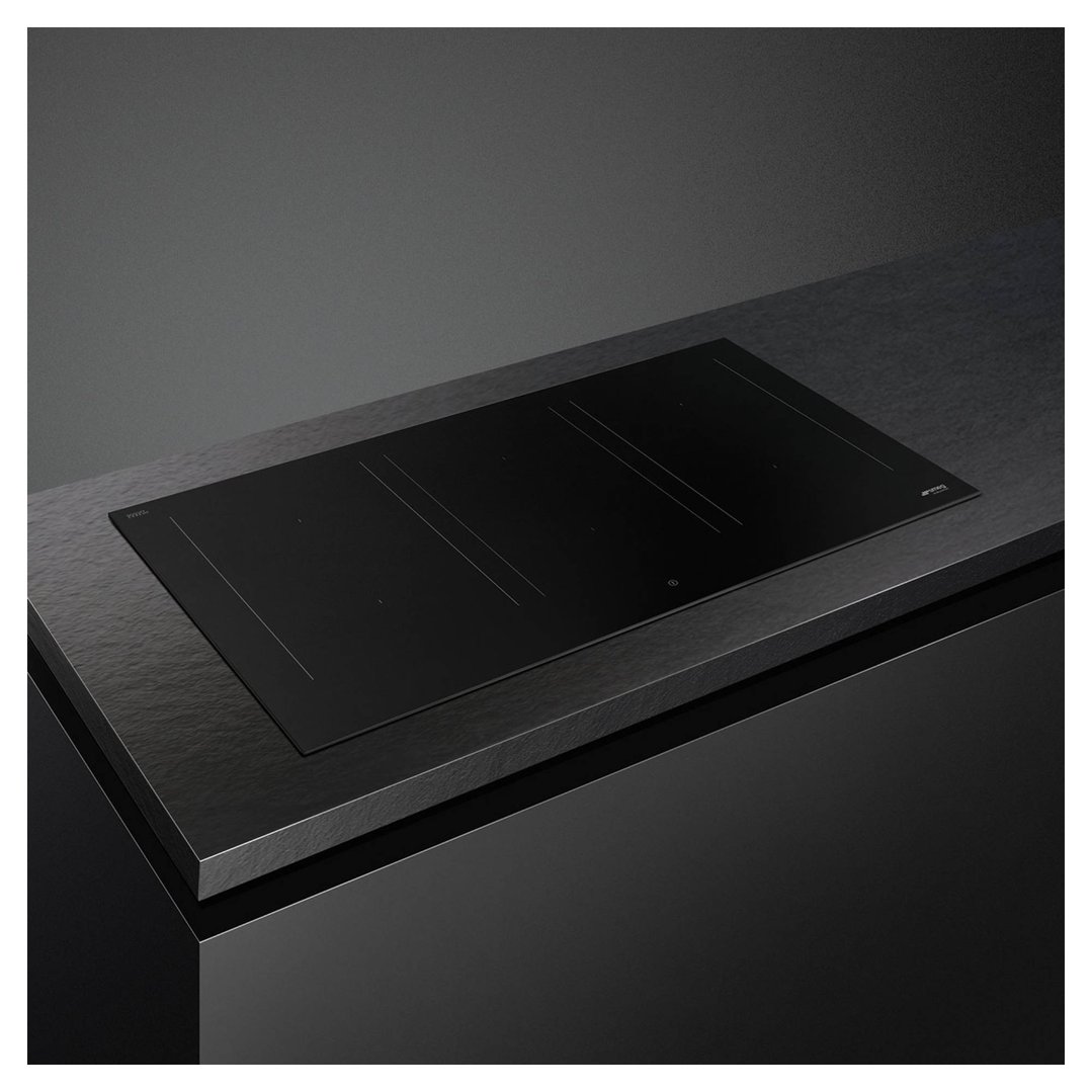 Black induction cooktop built into a dark countertop in a modern kitchen