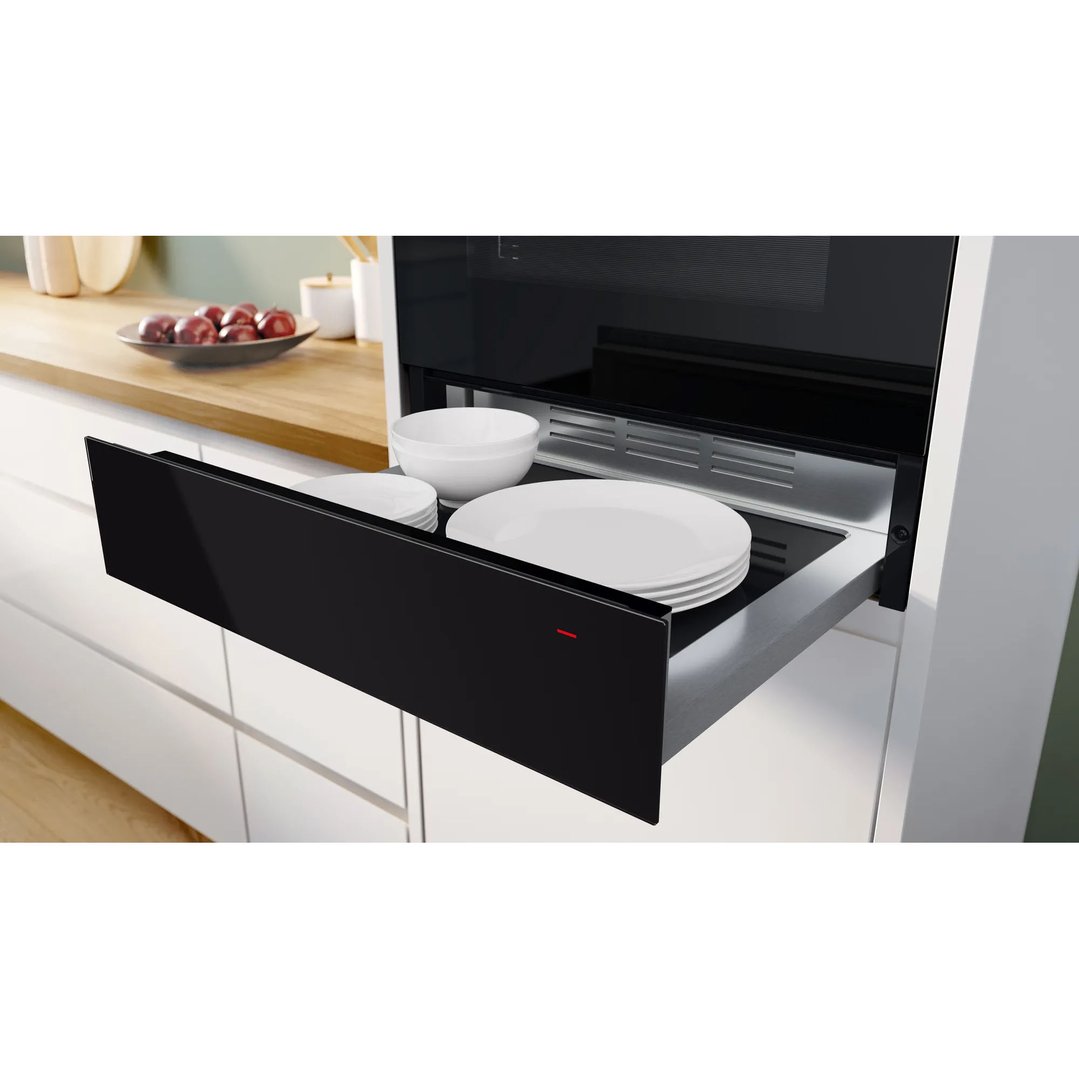 Black Bosch warming drawer open with white plates and bowls inside