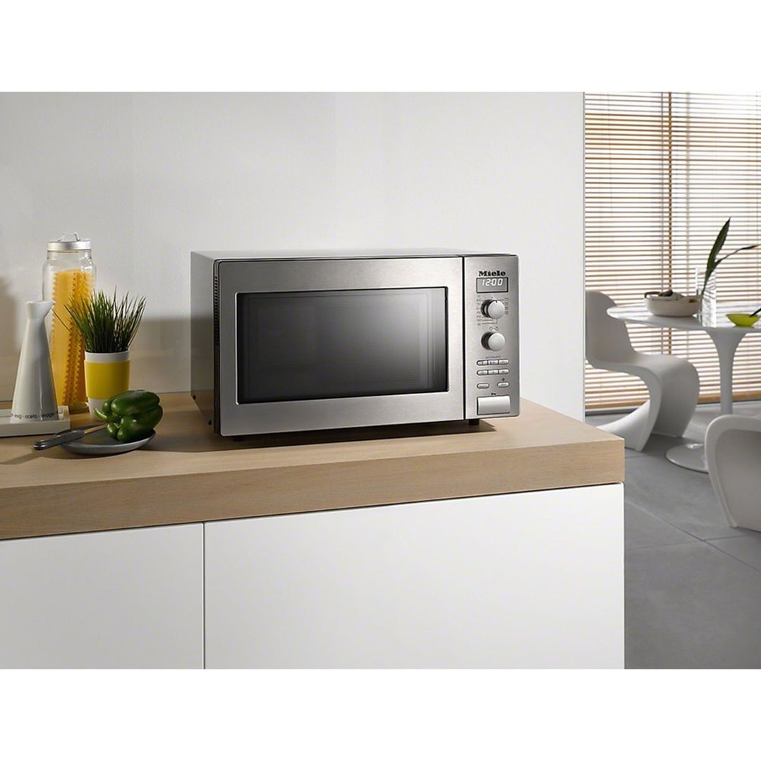 Stainless steel microwave oven on a wooden benchtop in a modern kitchen