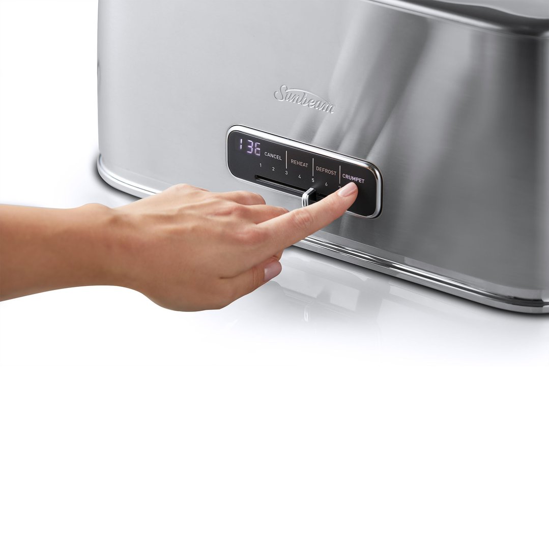 A hand pressing the 'CRUMPET' button on a Sunbeam toaster