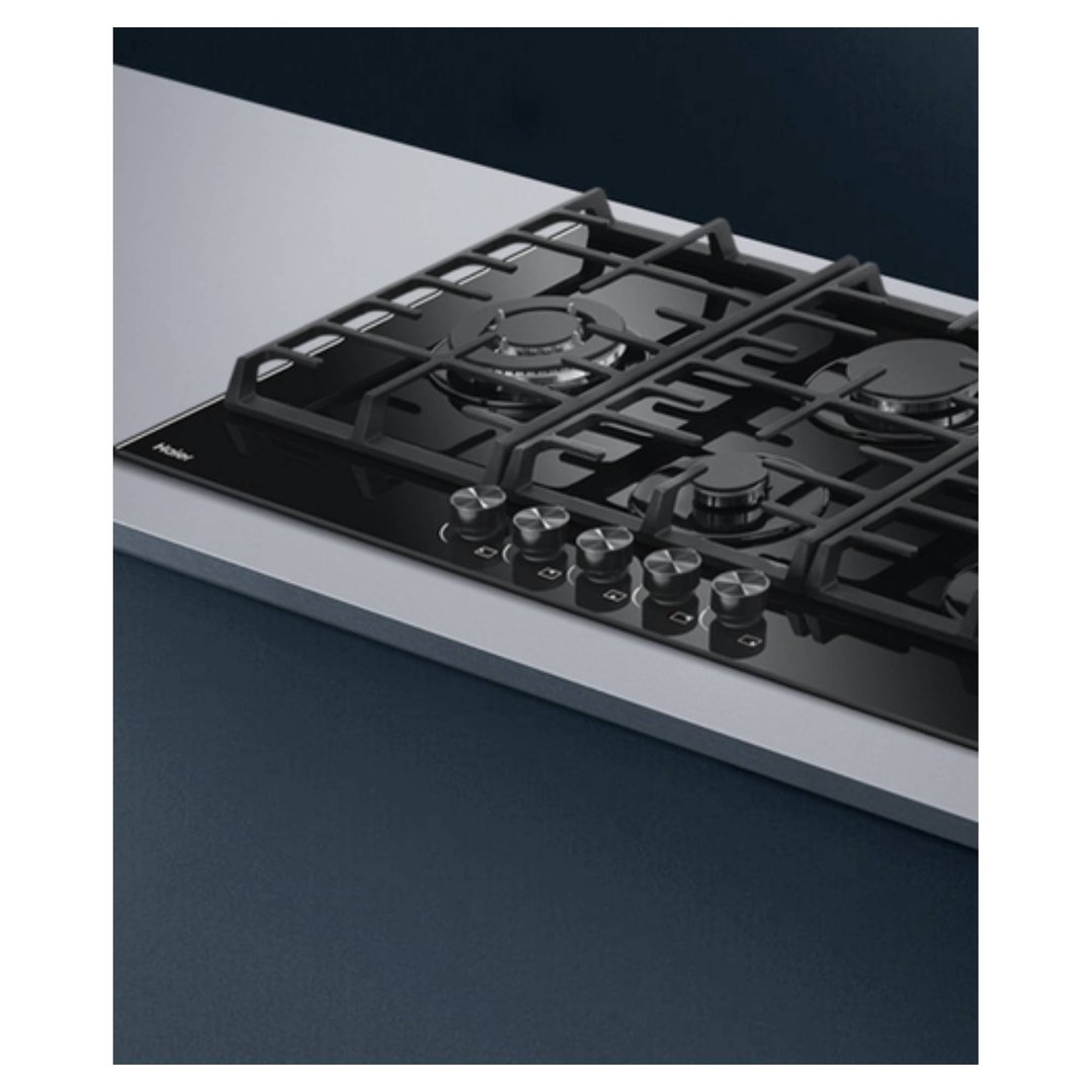 Black gas on glass cooktop with five burners in a modern kitchen setting