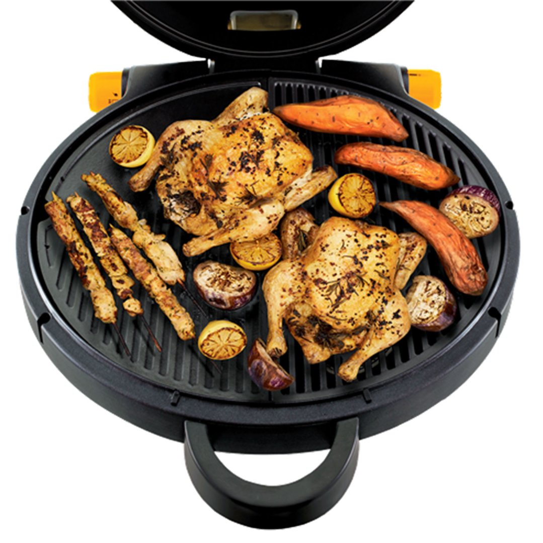 Open portable BBQ grill with two whole chickens, skewers, and vegetables