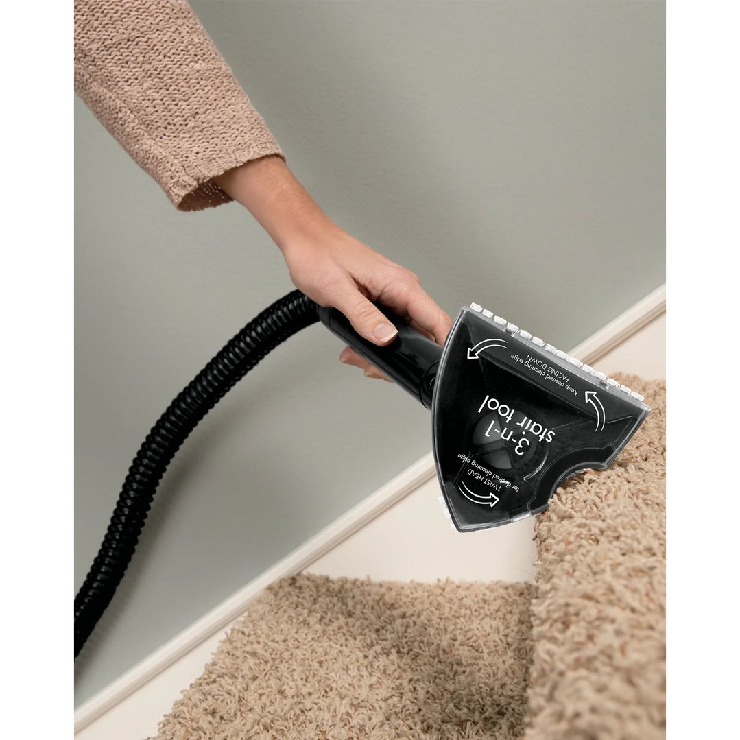 Hand using a carpet washer attachment to clean carpeted stairs