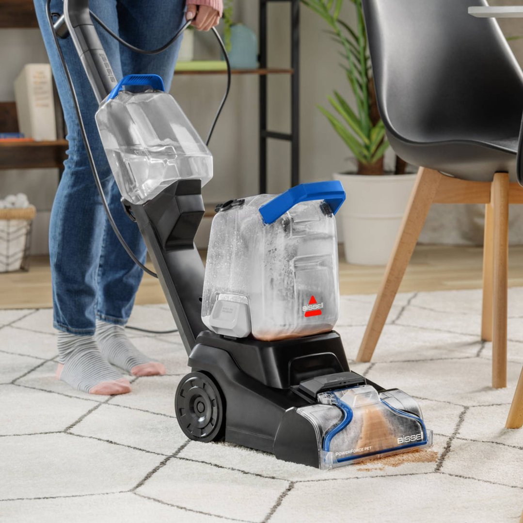 Person cleaning a white rug with a BISSELL PowerForce Pet carpet cleaner