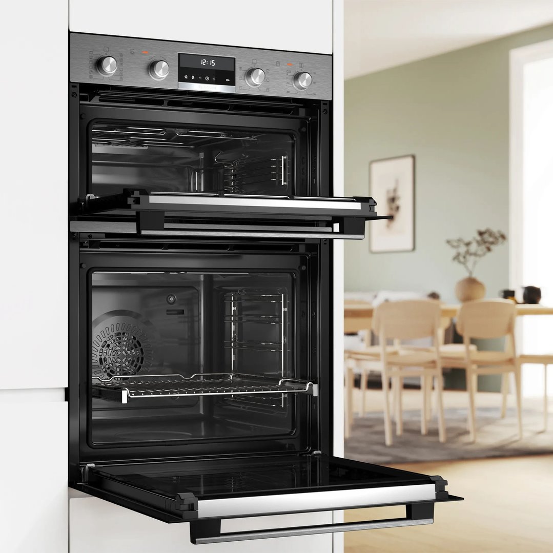 Built-in double oven with open doors in a modern kitchen setting